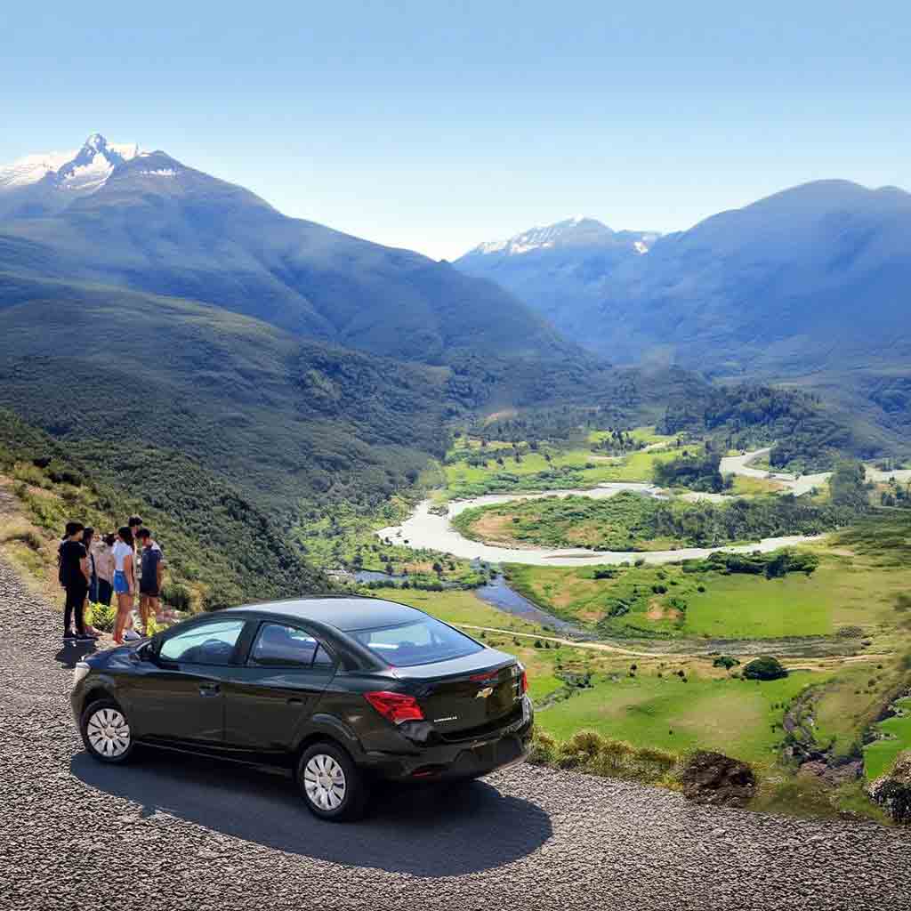 Chevrolet Prisma de alquiler recorriendo el Valle del Río Manso, cerca de San Carlos de Bariloche, con montañas y paisajes patagónicos al fondo. Rent a Car de Diversidad. Turismo Activo & de Naturaleza.